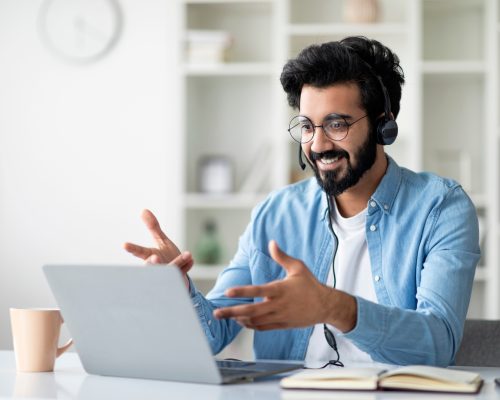 Online Coaching. Indian Male Tutor Making Video Call With Laptop And Headset